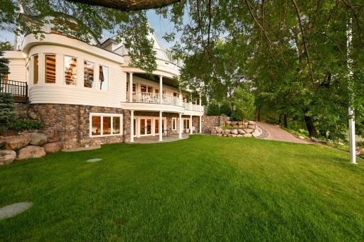 The walkout lower level opens to a lush, manicured lawn, while the upper-level balcony offers sweeping views and elegant outdoor living space. Thoughtfully landscaped with paver pathways leading you to the lake without stairs.