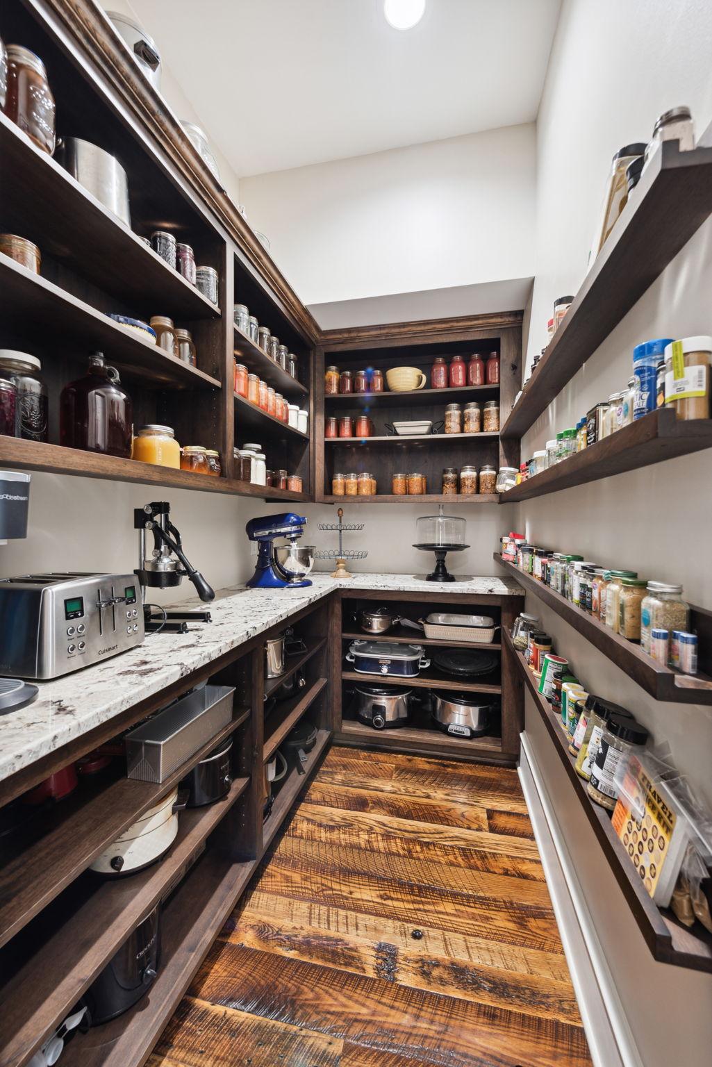 Walk-in pantry with custom wood shelving, granite countertops, and rich hardwood floors perfect for keeping kitchen essentials organized in style. A functional and elegant extension of this gourmet kitchen.