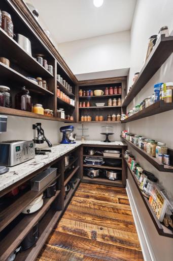 Walk-in pantry with custom wood shelving, granite countertops, and rich hardwood floors perfect for keeping kitchen essentials organized in style. A functional and elegant extension of this gourmet kitchen.