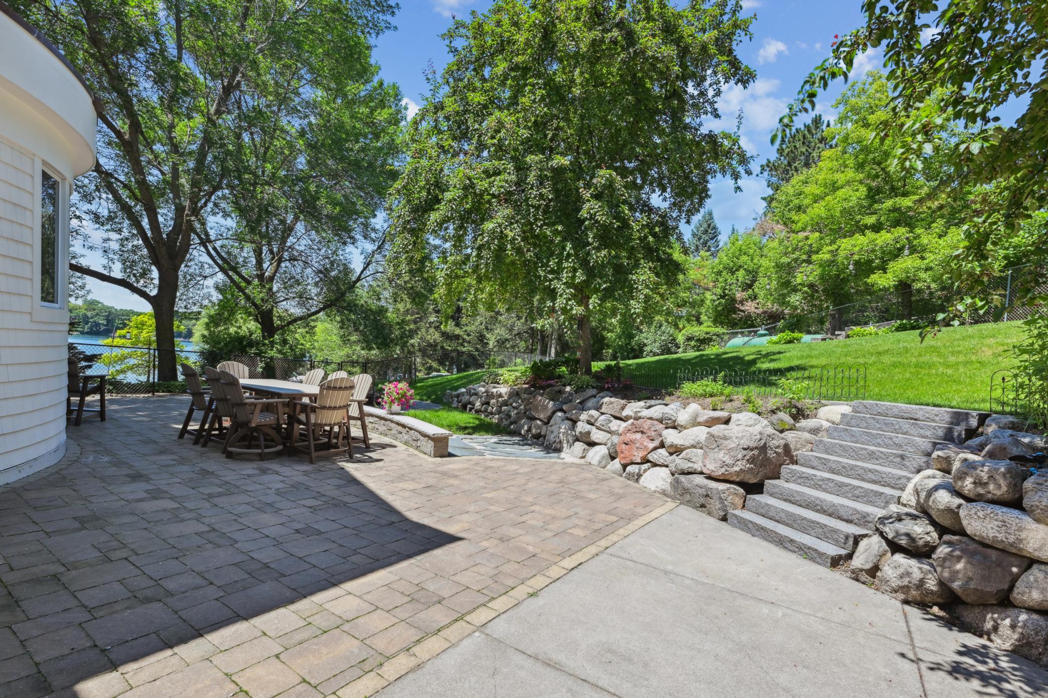 The paver patio wraps behind the garage, offering convenient access to both the mudroom and garage through patio doors, ideal for seamless indoor-outdoor living.