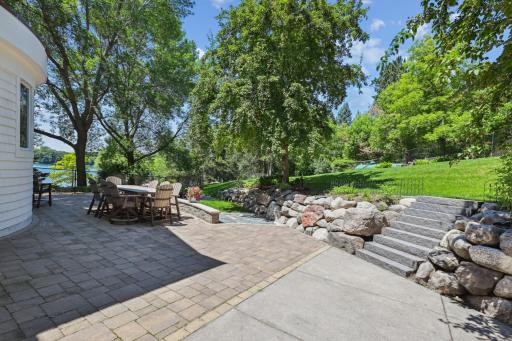 The paver patio wraps behind the garage, offering convenient access to both the mudroom and garage through patio doors, ideal for seamless indoor-outdoor living.