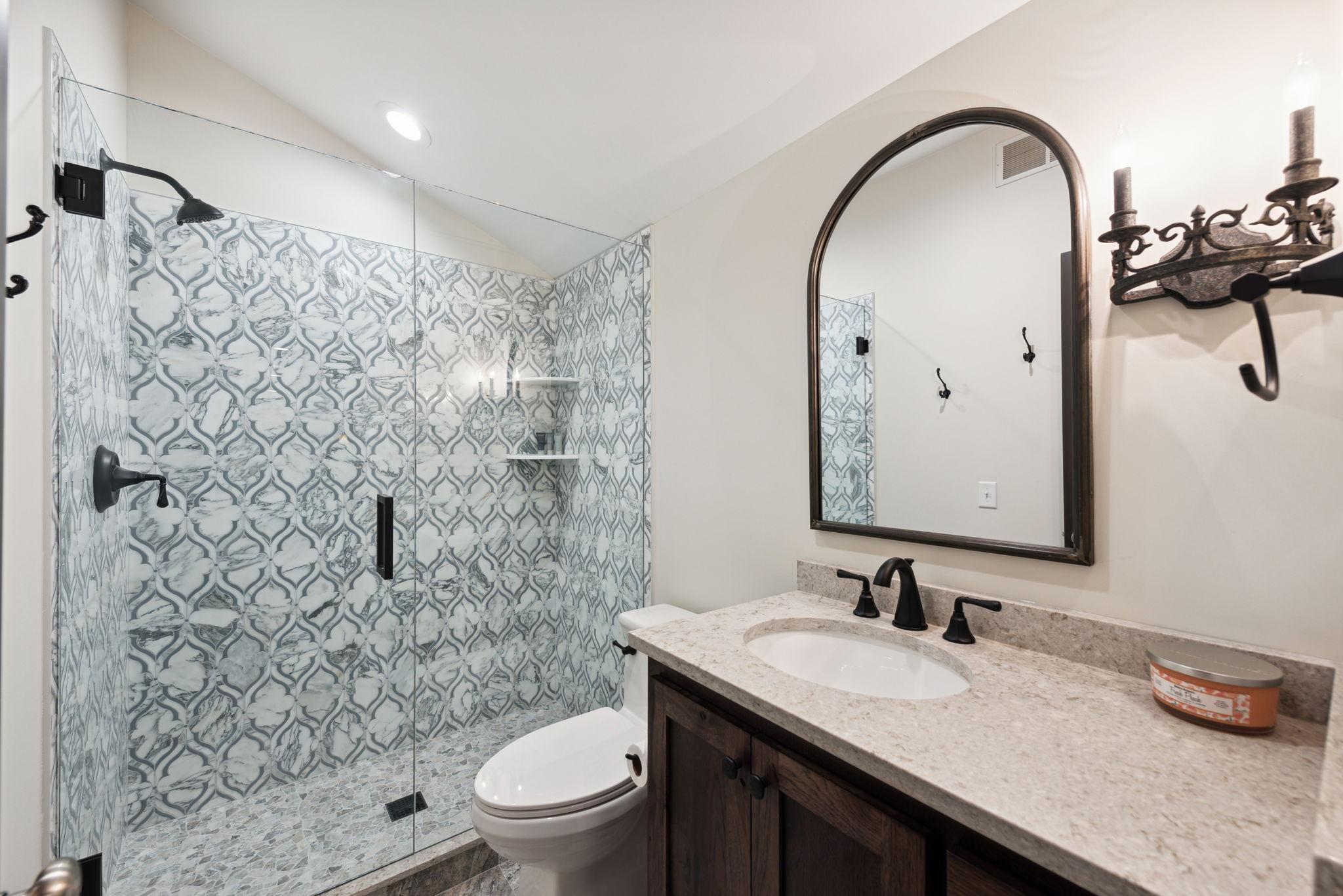 Located just off the second level living room, this elegant three-quarter bath features a stunning walk-in shower with designer tile and a rich wood vanity with stone countertop.