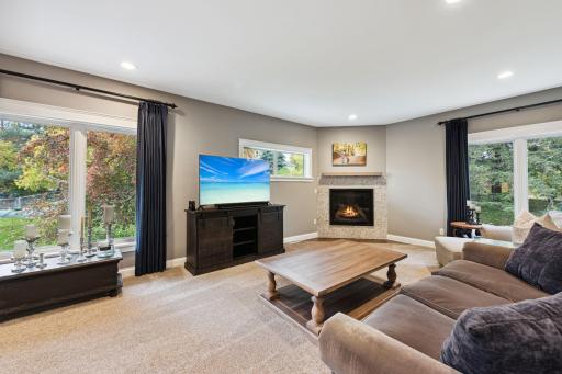 The upper level living room showcases a gas fireplace with elegant tile surround and access to a balcony deck overlooking the beautifully landscaped patio and gardens. An inviting space to unwind.