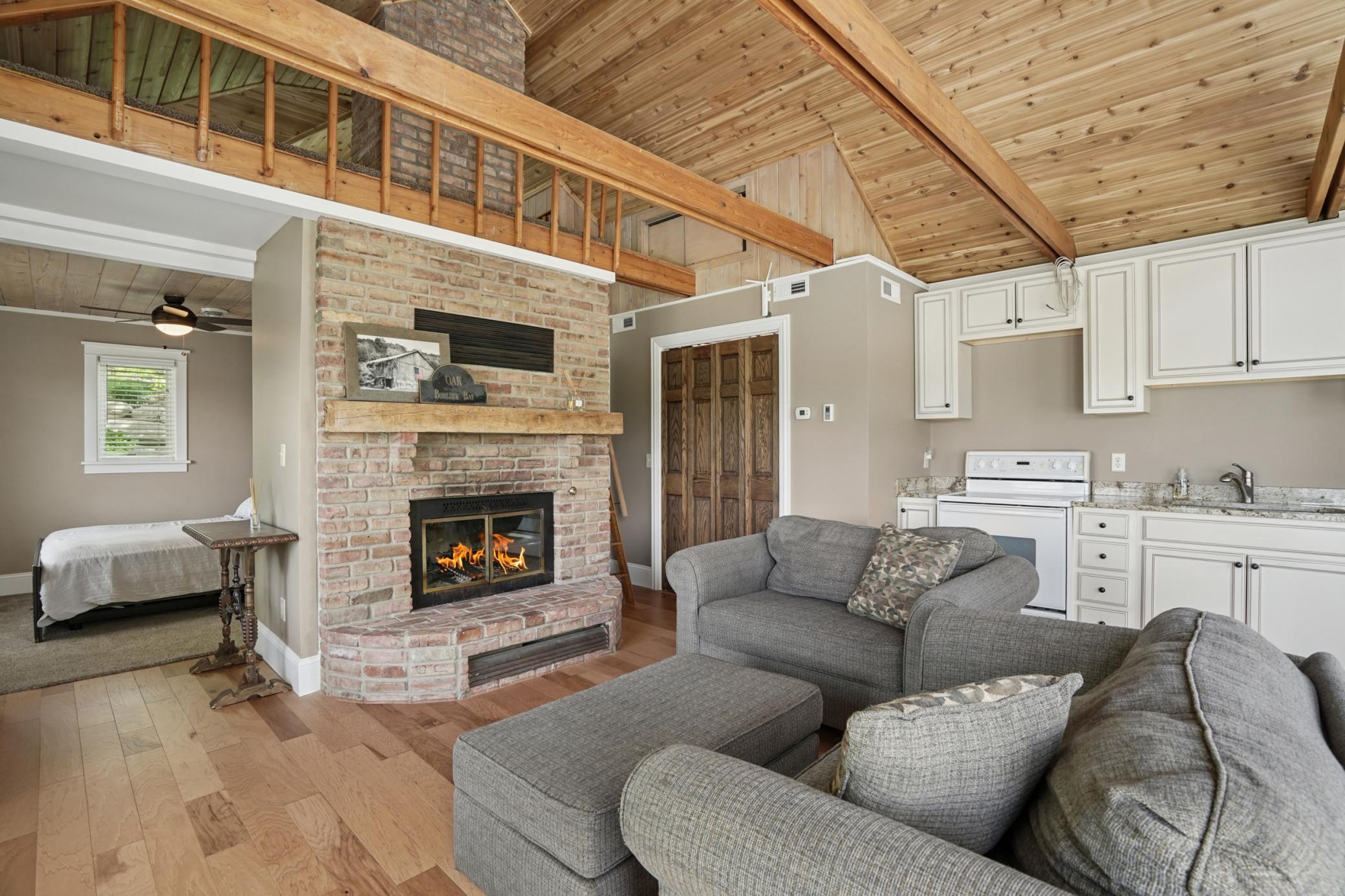 The spacious guest cottage features a full kitchen, and cozy living area with abundant natural light. The large patio door leads to a private patio surrounded by lush greenery, ideal for extended stays or entertaining lakeside guests.