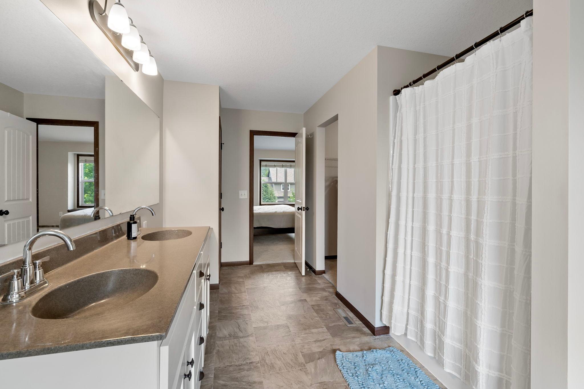 Primary bathroom with dual sinks, vanity counter space, linen closet and large walk in closet