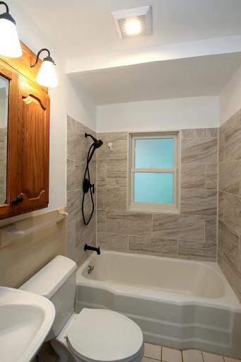 Main level full bath has a beautiful tile surround and updated fixtures