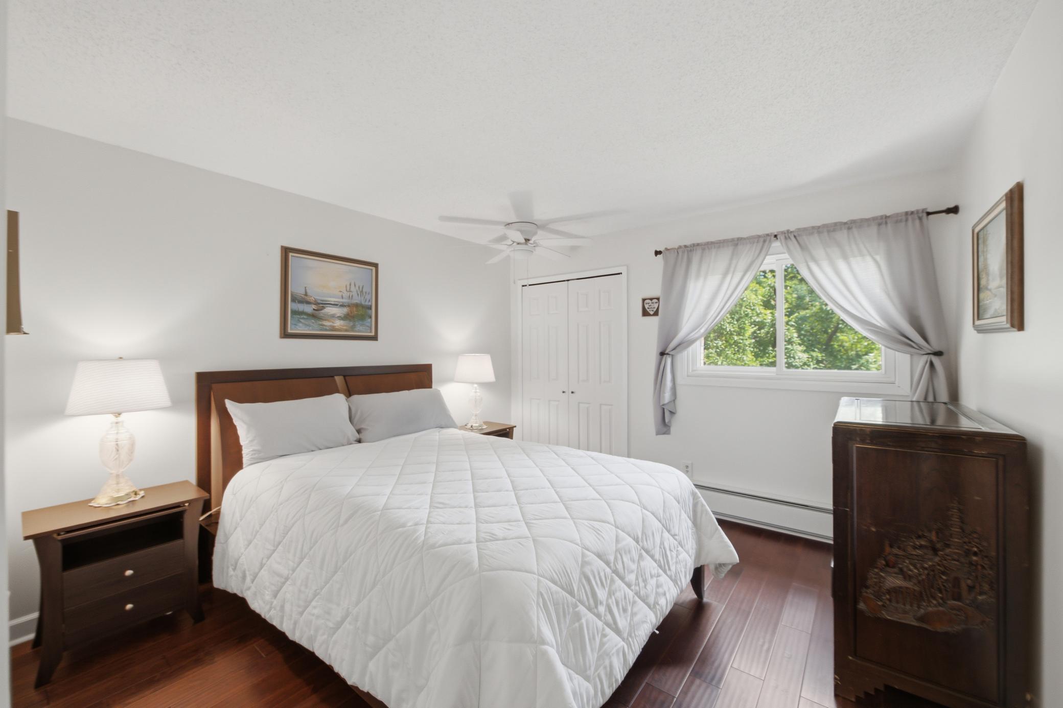 The secondary bedroom is set at the right side of the building and looks out to the trees in the side yard.