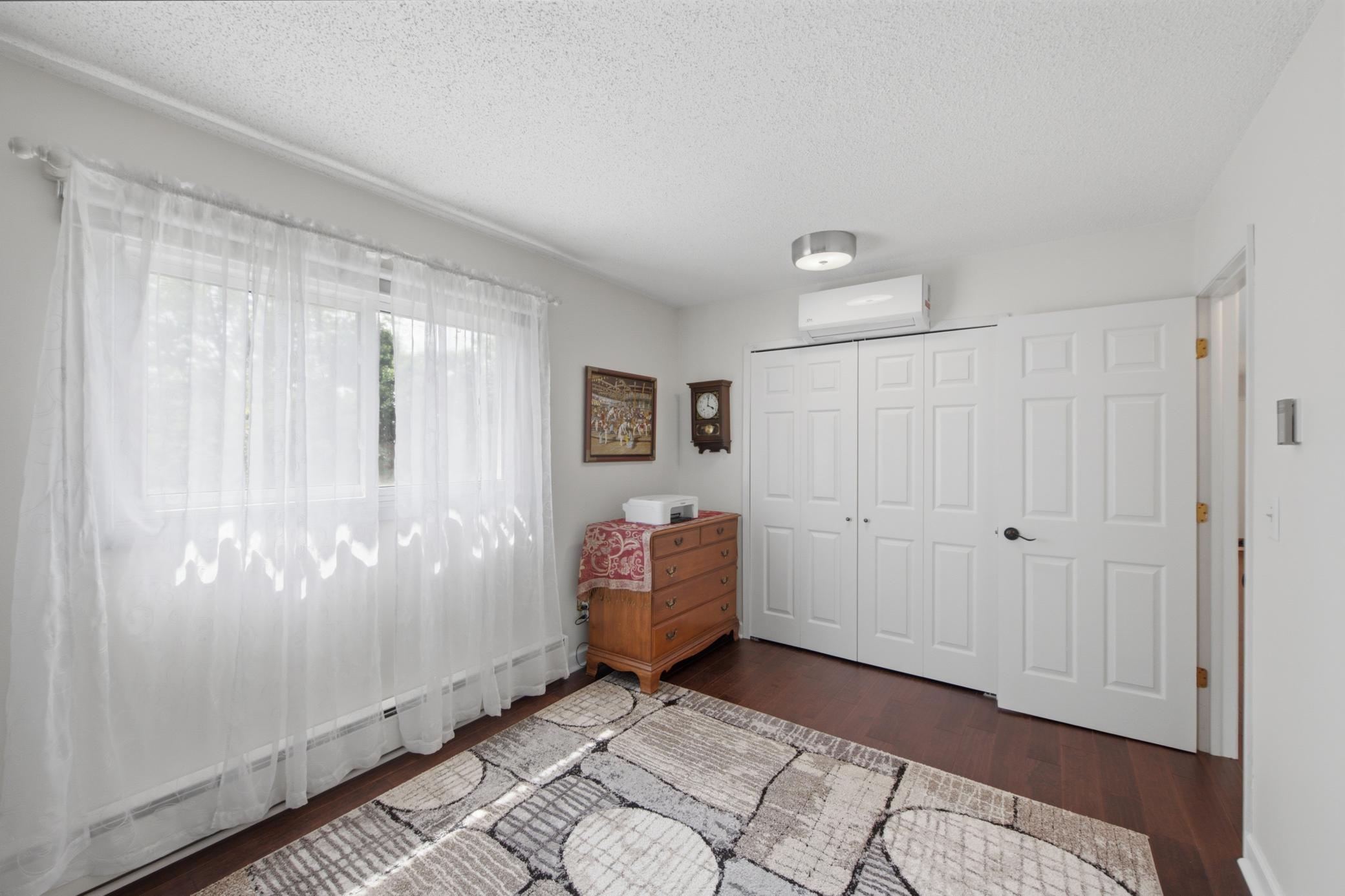 The primary bedroom - perfect alternative for guests, an office, or hobby room! The unit looks out to the expansive yard out front.