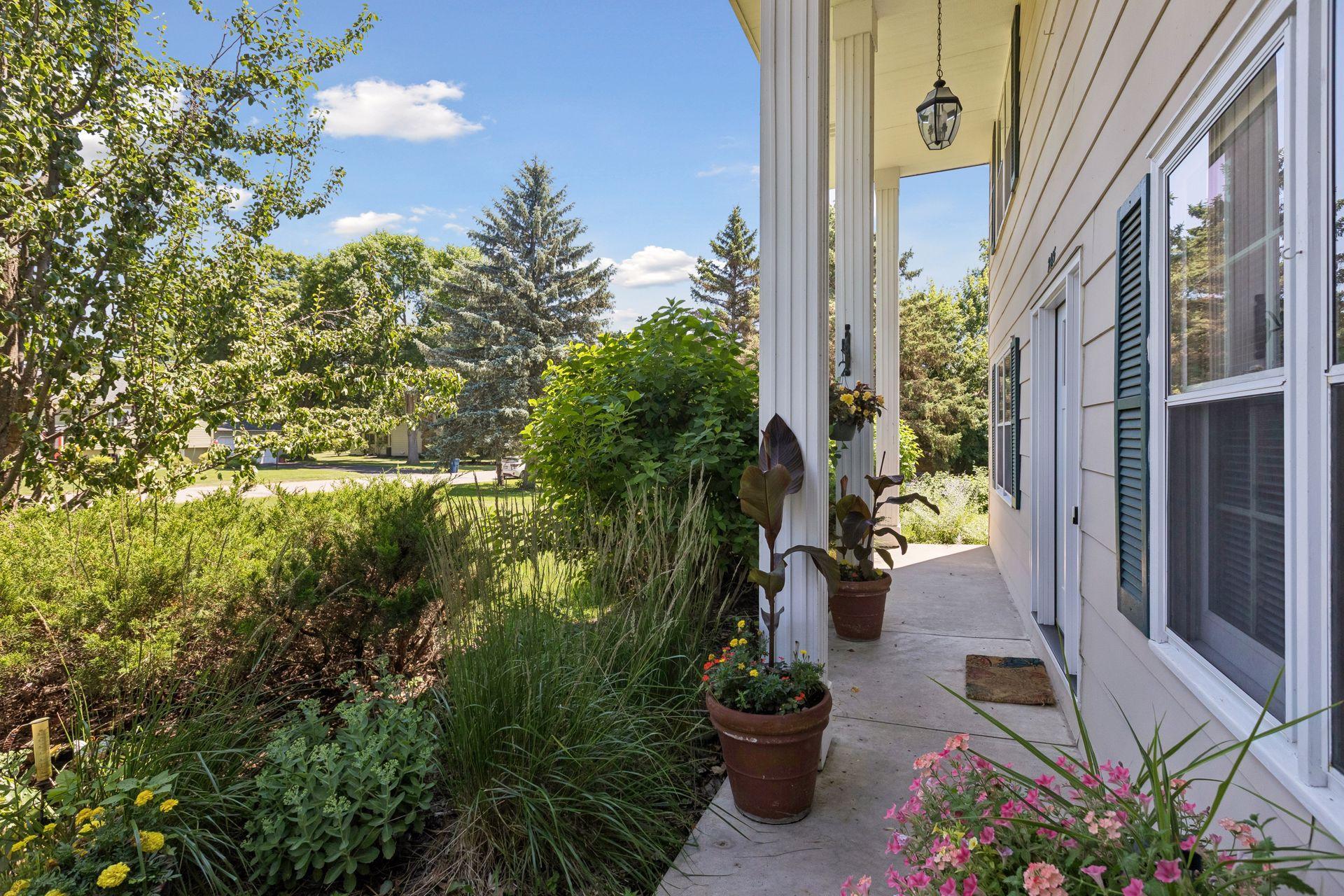 What a cute front porch with stately pillars and lush vegetation