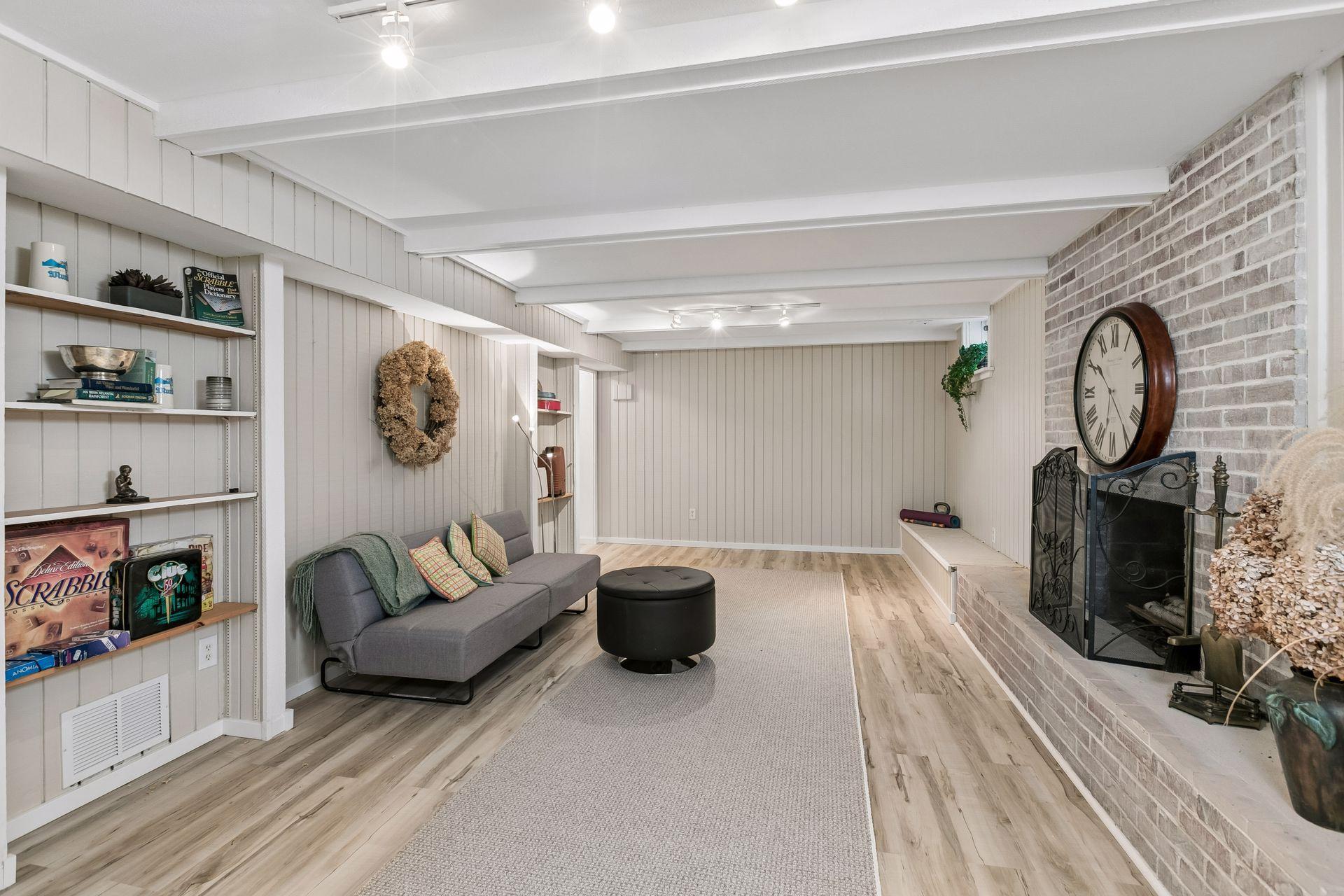 The amusement room in the lower level is equipped with an additional fireplace surrounded by white washed brick. Freshly painted beams add a brightness to the lower level
