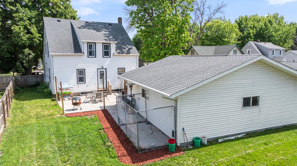 Concrete patio extends along the side of the garage with fresh landscaping surrounding the border
