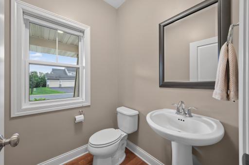 A sunlit main level powder room offers a welcoming touch for friends and family alike, blending classic finishes with everyday convenience in a bright, cheerful setting.