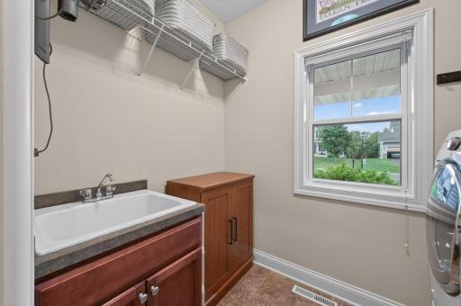 The laundry room offers a utility sink, upper shelving, additional cabinetry, and a large window--making household chores more efficient and enjoyable.