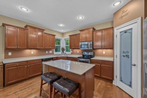 This beautifully designed kitchen features abundant cabinetry, a large center island with seating, granite countertops, stainless steel appliances, and a convenient walk-in pantry.