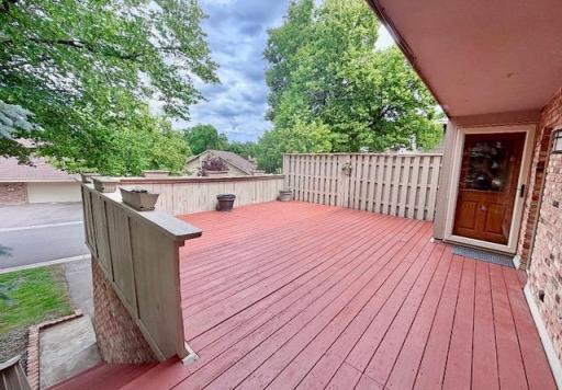 This is the beginning of the spacious, wraparound deck with privacy fencing. There is a storm door shielding the front door from the elements.