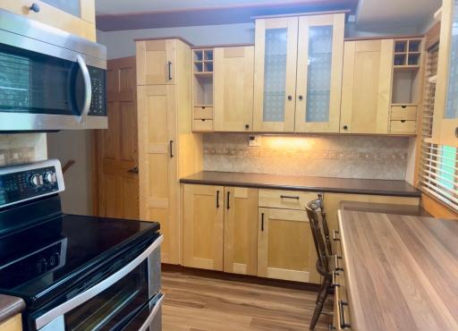 The birch wood cabinetry with glass fronts and black metal fixtures add value and beauty to this kitchen.