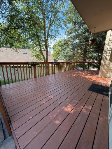 The cedar deck with railing wraps around the side of the home.