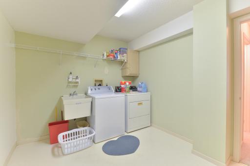 Generously sized lower-level laundry room with utility sink and plenty of space for storage.