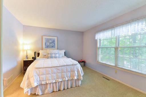Spacious main-level owner's bedroom featuring a large window overlooking the peaceful, tree-lined setting.
