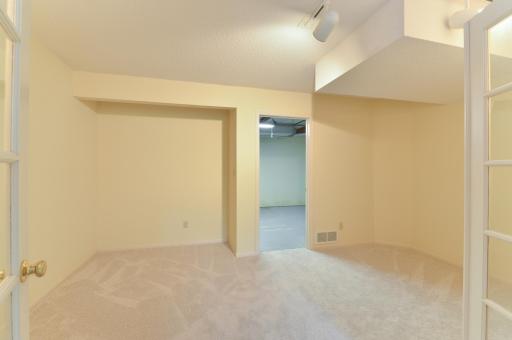 Versatile lower-level bonus room with French doors and built-in cabinetry and shelving.