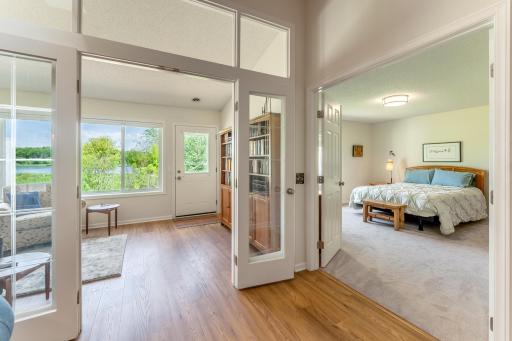 From the living room french doors lead to the sunroom or the primary bedroom.
