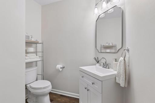 The half bath is oversized and has a new vanity, faucet, mirror and lighting.