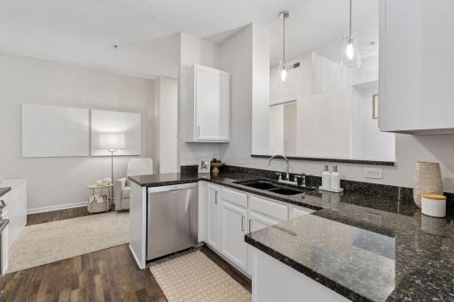 A stainless dishwasher is at one end and a slide out refuse cabinet is at the other end. Note the adjoining room....