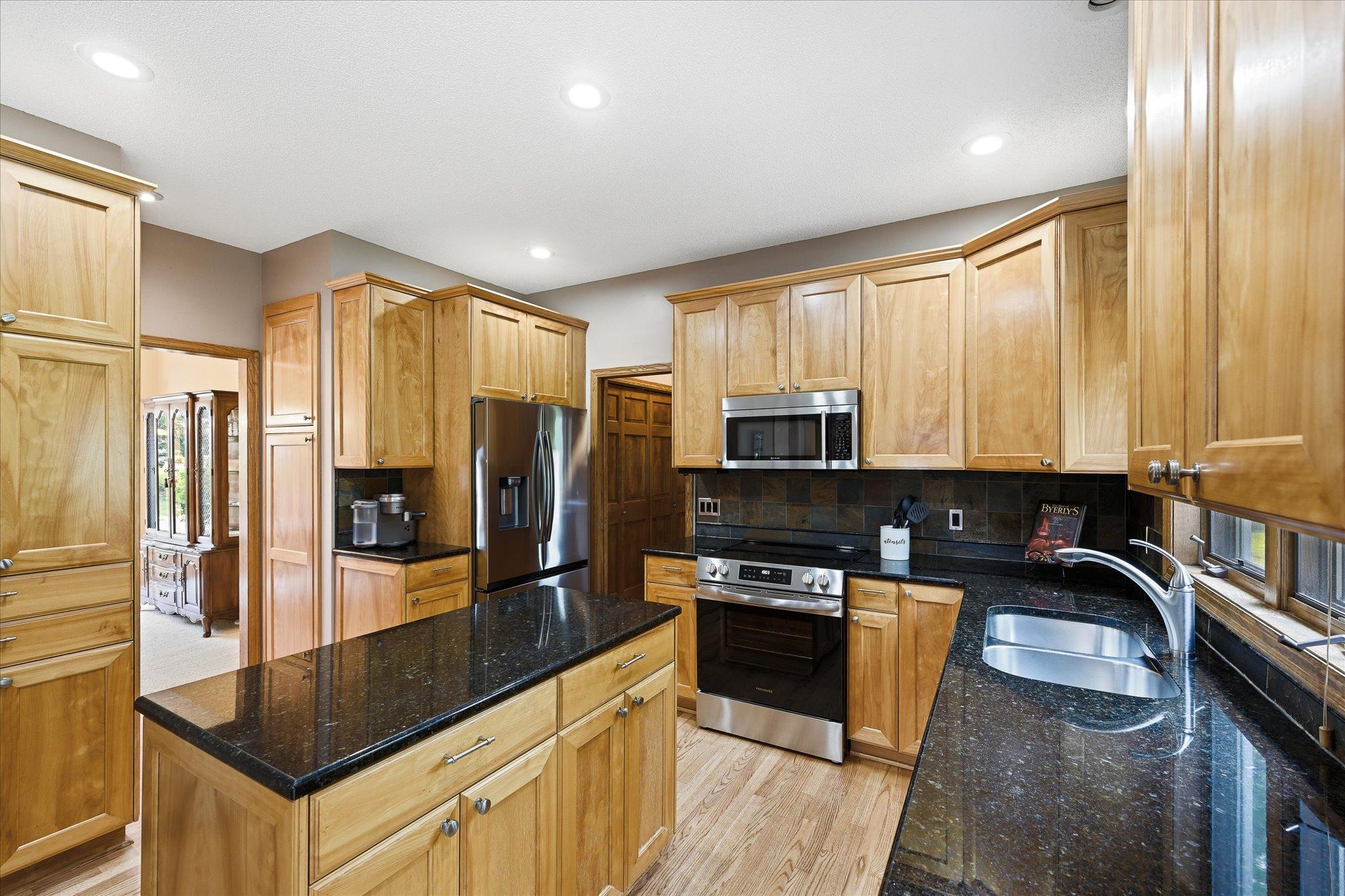 The remodeled kitchen features generous cabinetry, beautiful countertops, and a center island with plenty of room for meal preparation and gathering.