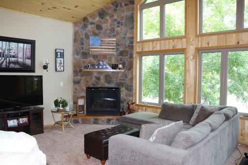 Living room with stone fireplace and floor to ceiling windows looking out at the lake