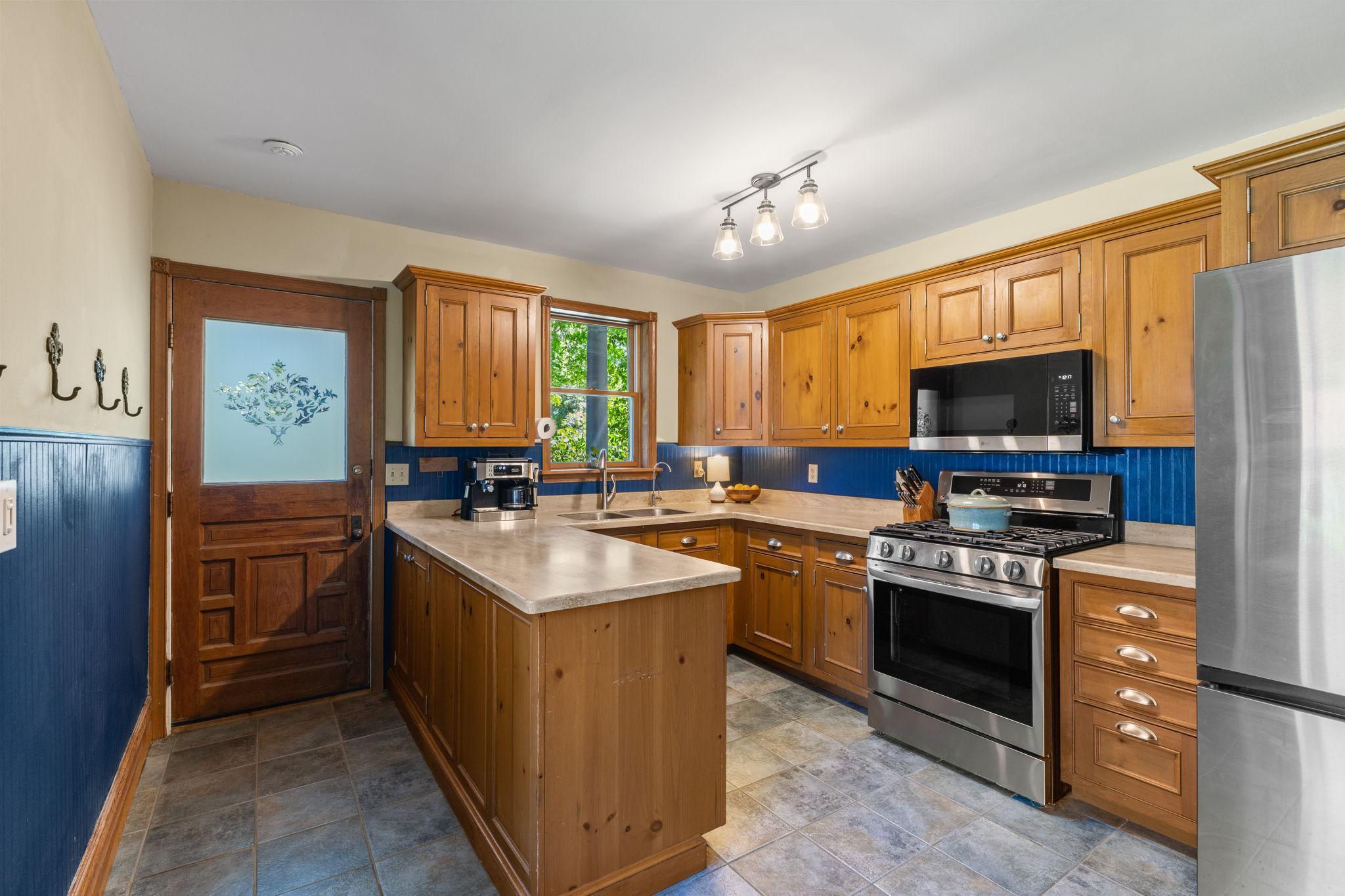 Updated kitchen with stainless appliances, Corian countertops, tile floor and solid wood cabinets