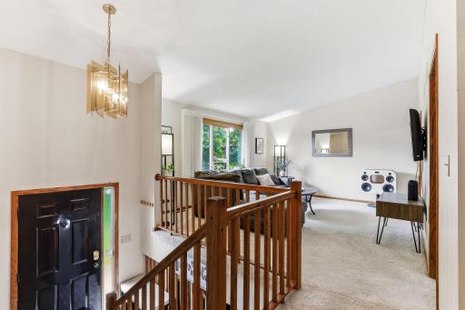 Bright and inviting upper-level living room featuring neutral finishes, plush carpeting, and a large picture window that fills the space with natural light.
