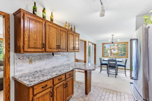 Rich oak cabinetry provides abundant storage and complements the Cambria quartz countertops and updated tile backsplash. The open layout offers plenty of room for everyday dining while maintaining an easy connection to the kitchen and living areas.