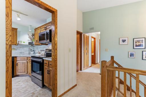 Open upper-level hallway with oak railings overlooking the foyer. Convenient access to the kitchen, bedrooms, and bath, with neutral finishes and an airy, open feel throughout.