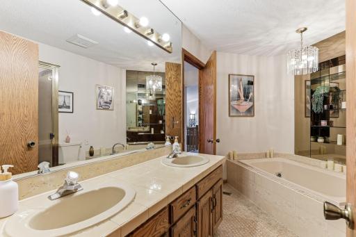 Spacious primary walk-through bath featuring a double-sink vanity, jetted soaking tub, and separate shower.
