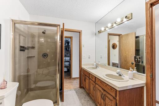 Primary bath walk-through with a double-sink vanity, walk-in shower, and easy access to the walk-in closet.