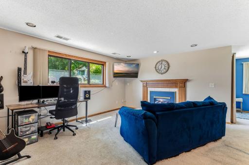 Lower-level family room with a gas fireplace, large daylight window, and plenty of space for gathering or movie nights.