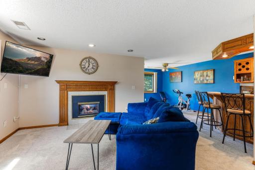Spacious lower-level family room featuring a gas fireplace, daylight windows, and an open layout. Plenty of space for relaxing, entertaining, or creating a game area, with easy flow to the adjacent bar and recreation space.