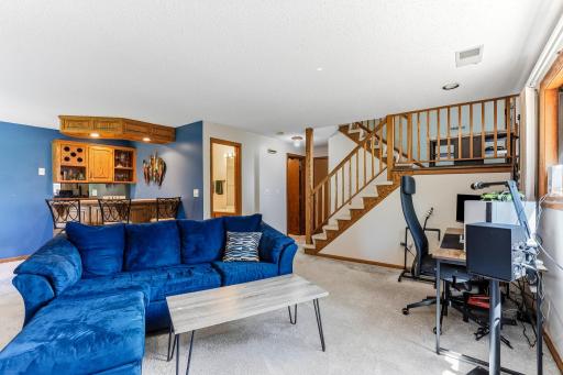 Lower-level family room with an open layout, gas fireplace, and built-in wet bar nearby for easy entertaining.