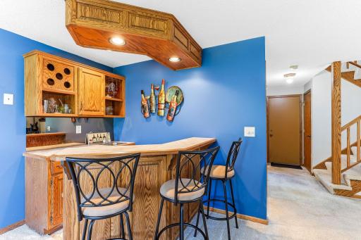 Lower-level wet bar with built-in cabinetry, wine storage, and bar seating. A great space for entertaining guests, serving refreshments, or creating a dedicated game-day gathering area adjacent to the family room.