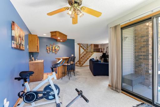 Lower-level recreation area featuring a wet bar, open gathering space, and sliding glass door access to the patio.