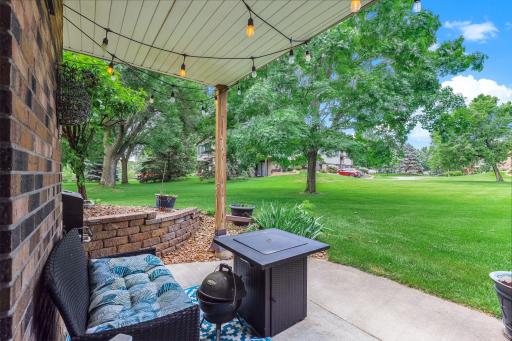Covered patio overlooking a beautifully maintained green space with mature trees and extensive lawn. A peaceful outdoor retreat for relaxing or entertaining.