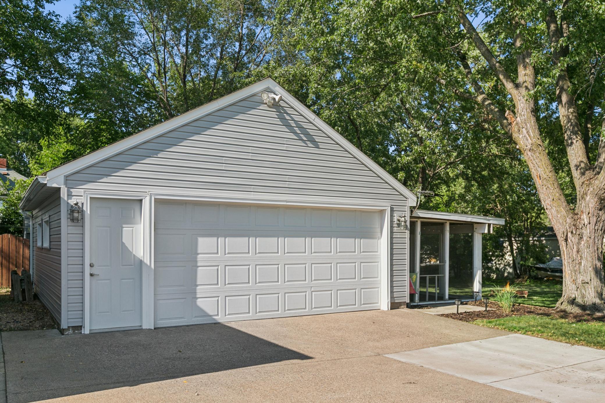 Oversized two-stall garage with attached screened porch. New concrete driveway in 2022. Insulated garage door, gutters and automatic garage door opener.