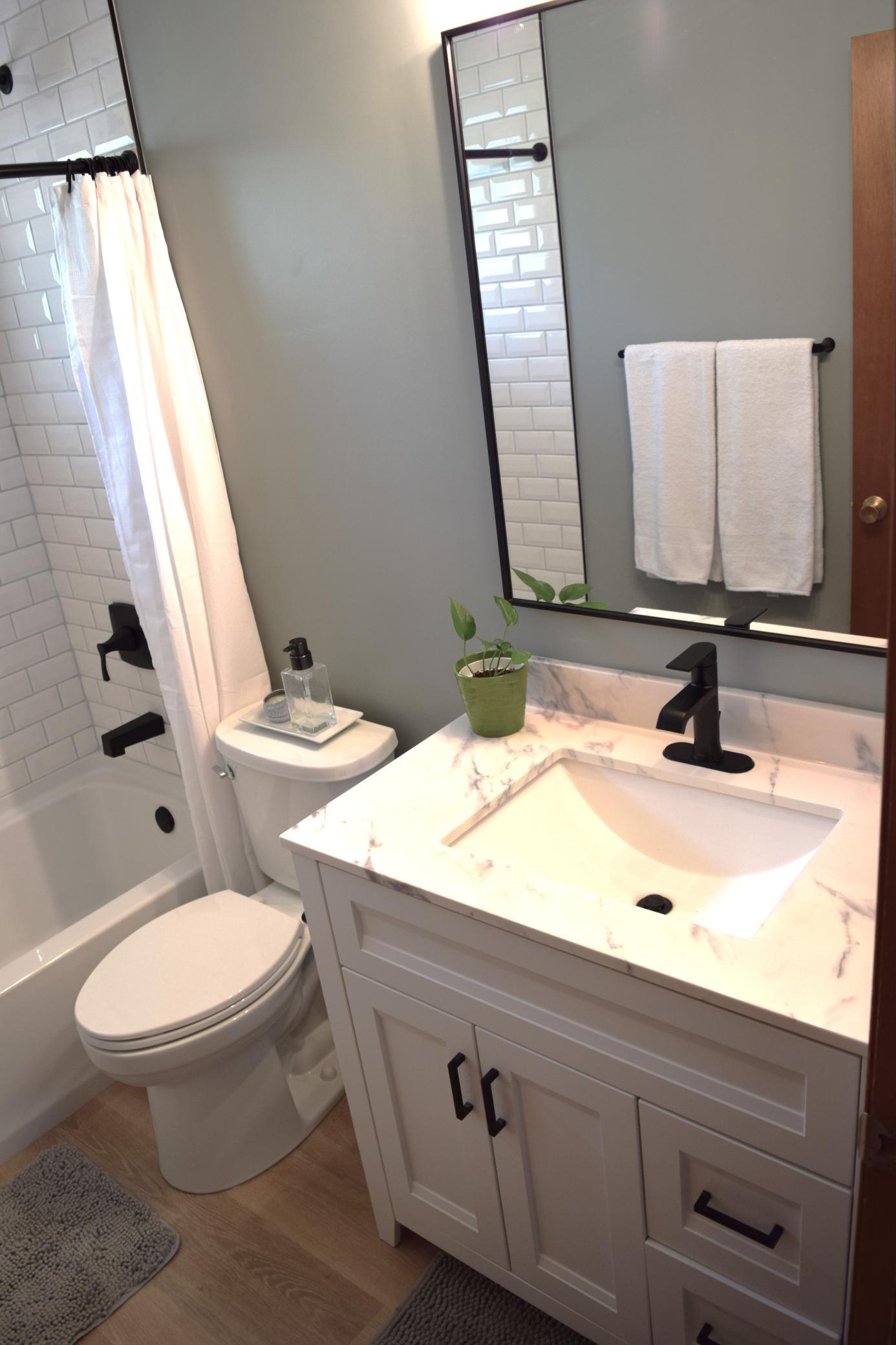 Less than 1 month old, this completely remodeled main floor full bathroom has a marble top vanity, new LVT flooring and a custom tile bathtub surround!