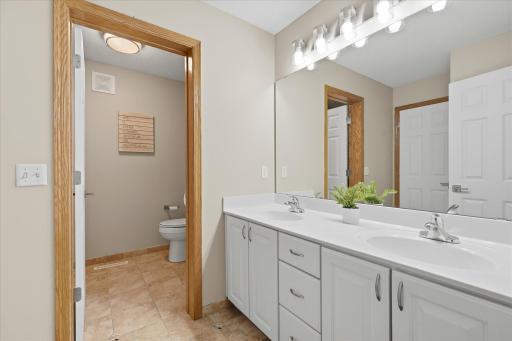 Full bathroom on the upper level offers dual sinks, updated lighting, fresh neutral paint and a door to closet off the toilet and shower area.