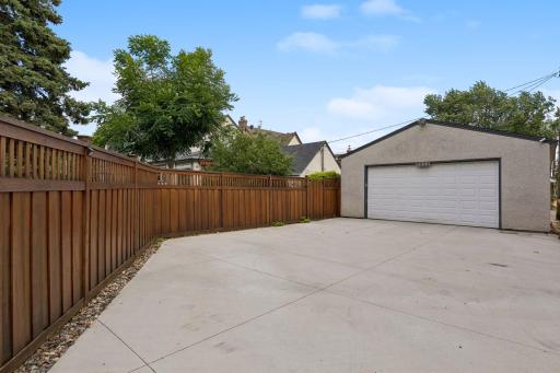 Two-car detached garage and privacy fencing, newer concrete driveway with river stone border accent.