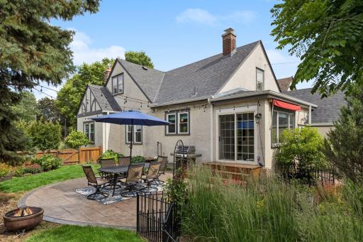 Rear view of home from the expansive, heirloom perennial gardens. Circular stamped concrete patio connects to the sliding patio doors and maximizes the fenced corner lot. Roof new 2021.