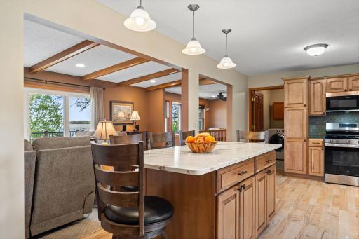 Large center island with quartz countertops. Seamless open floor plan, large windows fill this space with natural light and serene lake views in the background.