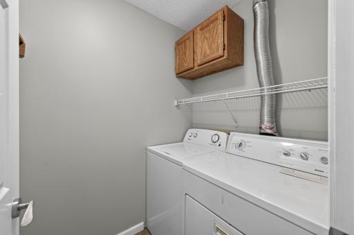 Convenient upper-level laundry room with built-in storage cabinet and shelving.