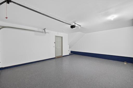 Attached two-car garage with durable epoxy-coated floor and additional storage space.