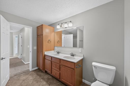 Dual vanity and additional linen cabinetry offer exceptional storage.